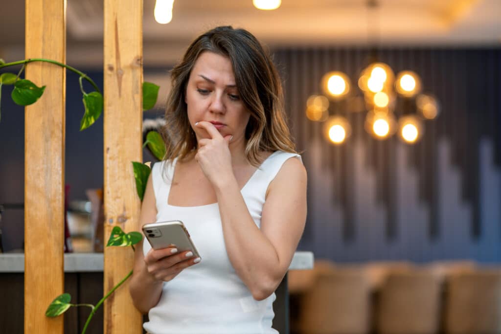 Outsmarting Scammers: How to Avoid Investment Scams in New Zealand 1 Woman who received a spam message on her cell phone reads the message.