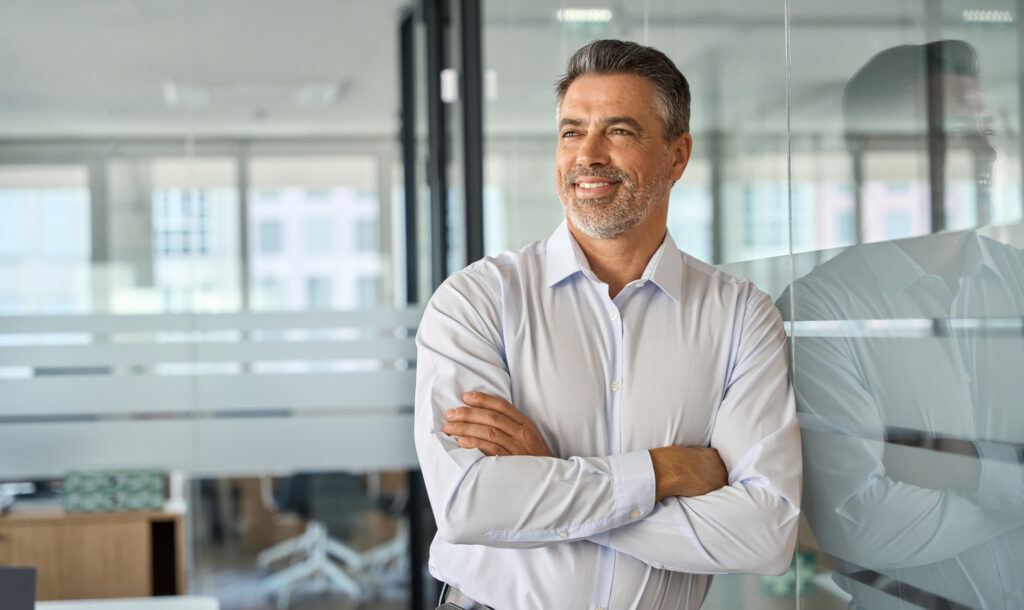 Businessman standing in office arms crossed looking away